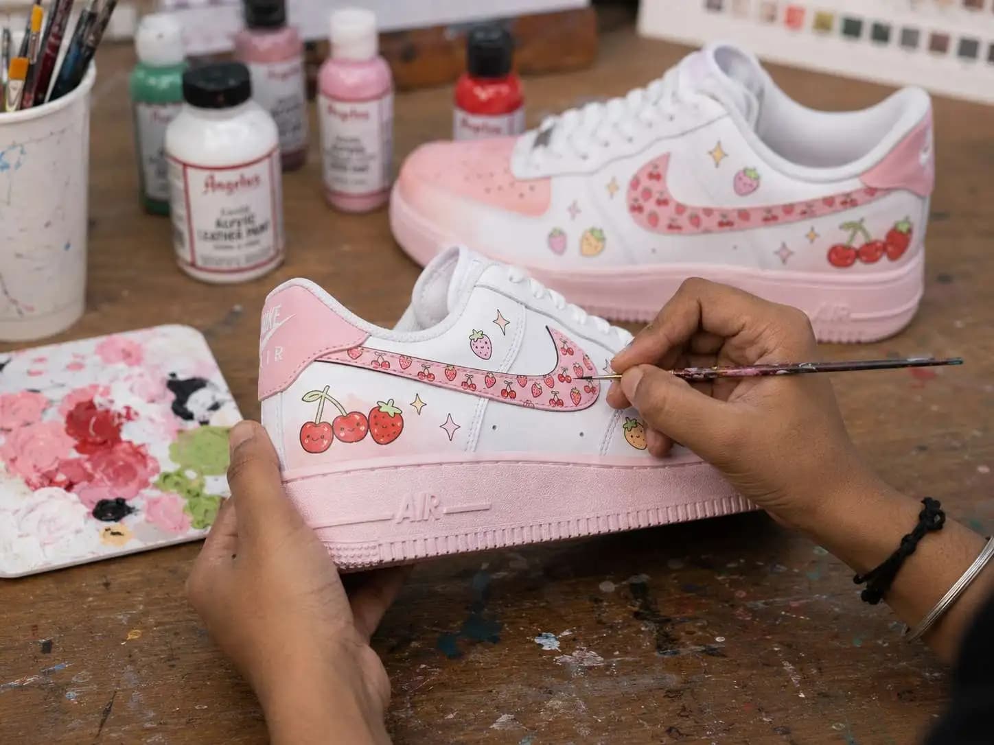 Indian artist hand-painting a Cherry Pop Air Force 1 sneaker